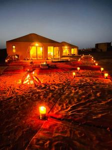 une rangée de bougies brûlant dans le sable la nuit dans l'établissement Mhamid luxury camp, à M'Hamid El Ghizlane