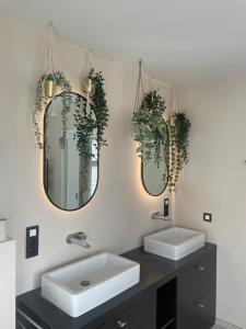 a bathroom with two sinks and two mirrors at Aurelia B&B in Lommel +42 photos