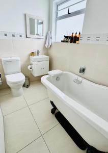 a white bathroom with a tub and a toilet at Cosy Family 2-Bedroom Cottage with Braai, Fireplace, Kitchen near Strand Beach in Strand +33 photos