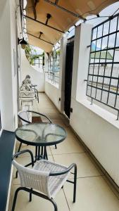 a balcony with two tables and chairs and windows at Cosy Family 2-Bedroom Cottage with Braai, Fireplace, Kitchen near Strand Beach in Strand