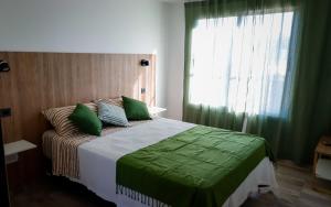 Un dormitorio con una cama con sábanas verdes y una ventana. en La Francisca, Alojamiento, en San Rafael