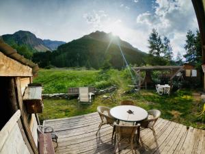 a table and chairs on a wooden deck with a mountain at Le Refuge des Boussardes in Le Monêtier-les-Bains