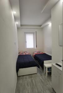 deux lits dans une petite pièce aux murs blancs dans l'établissement porto, à Grado