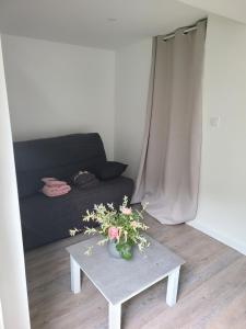 un soggiorno con un divano e un tavolo con fiori di Studio indépendant a Saint-Égrève