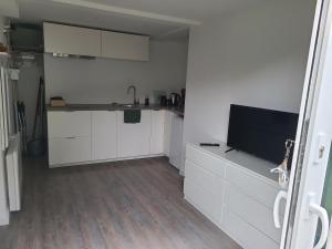 una cucina con armadi bianchi e una TV a schermo piatto di Studio indépendant a Saint-Égrève
