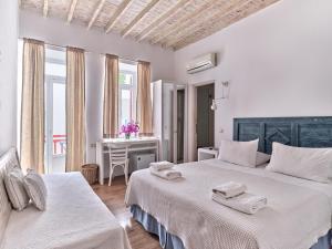 a white bedroom with two beds and a table at La Maison Kalogera in Mikonos +54 photos
