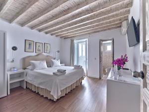 a white bedroom with a bed and a wooden ceiling at La Maison Kalogera in Mikonos
