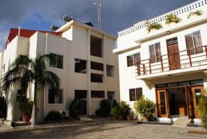 a white building with a palm tree in front of it at pendo cozy cottages in Kwale
