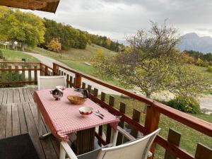 a table and chairs on a wooden deck with a view of a river at Le Serre in Chorges