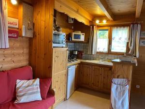 a kitchen with wooden cabinets and a red couch in a cabin at Le Serre in Chorges
