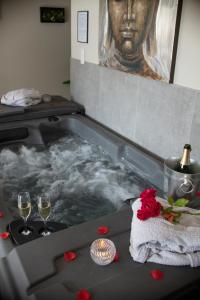 a hot tub with two glasses of wine and roses at Eden House, Cocon sensuel et romantique avec jacuzzi in Carpentras