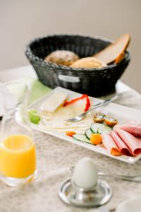 a plate of food and a basket of bread and orange juice at Gästehaus Fechtig in Hergensweiler +37 photos