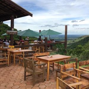 a restaurant with wooden tables and green umbrellas at Apartamento Cachoeira Cipriano in Botucatu