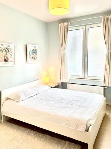 Un dormitorio con una cama blanca y una ventana. en Beautiful 2 bedroom familiar luxury apartment, en Bruselas