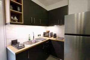 a kitchen with black cabinets and a stainless steel refrigerator at Elaion guest house in Athens