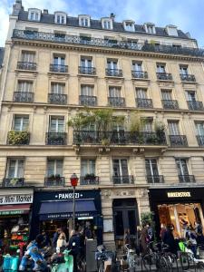 un gran edificio con gente parada frente a él en APPARTEMENT AU CŒUR DE MARAIS DANS CENTRE de PARIS, en París