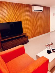 Il comprend un salon doté d'un canapé orange et d'une télévision à écran plat. dans l'établissement Acogedor Apartamento Marbella ideal familias, à Carthagène des Indes