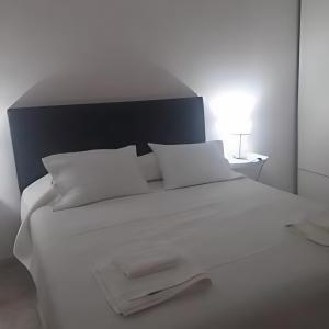 a white bed with white pillows and a lamp at Bahiaxdia Saavedra in Bahía Blanca