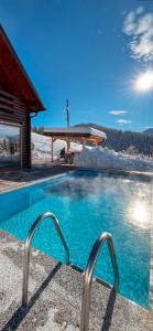 ein Schwimmbad vor einem Haus im Schnee in der Unterkunft Bujtina Gentiana in Peja