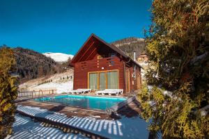 ein Blockhaus mit einem Pool im Schnee in der Unterkunft Bujtina Gentiana in Peja