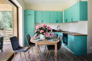 a kitchen with blue cabinets and a wooden table with pink flowers at Kosiedlisko in Kraśnik