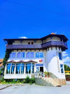 a large white building with a balcony on top at Vila Belvedere in Haţeg