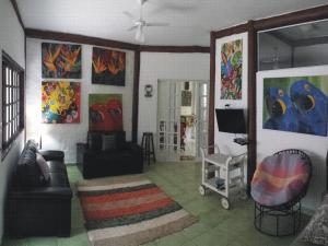 un soggiorno con opere d'arte alle pareti di Casa do Joca - Ilhabela a Ilhabela