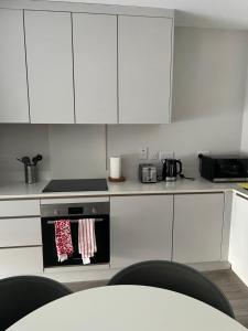 Una cocina con gabinetes blancos y un horno de estufa. en Spacious shared apartment with private Bathroom Dublin, en Lucan