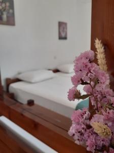 a bed with white sheets and purple flowers on a table at Antigoni Apartments 'Lavender Room' in Milatos