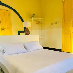 a bedroom with a white bed with a yellow wall at Hostal 1545 in Ríohacha