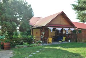 a house with a porch and yellow chairs in a yard at Agroturystyka pod Czarną Sosną in Biały Ług