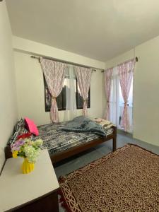 a bedroom with a bed and a table with flowers on it at Samendo-Retreat Homestay in Sukhia Pokhari