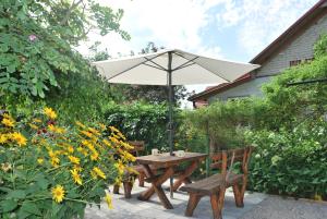 a wooden table and benches with an umbrella at Agroturystyka pod Czarną Sosną in Biały Ług