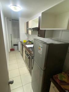 a small kitchen with a refrigerator and a sink at Departamento Peñuelas in La Serena
