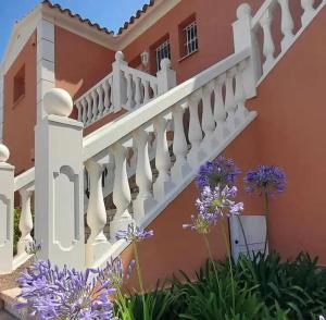 una escalera en el lateral de una casa con flores púrpuras en Oliva Nova Playa Golf MET, en Oliva