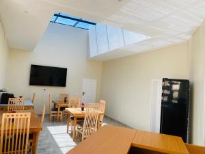 The Residence Hills BnB في هراري: غرفة بها طاولات وكراسي وتلفزيون بشاشة مسطحة