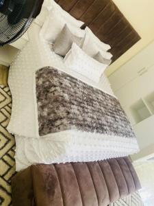 The Residence Hills BnB في هراري: سرير عليه ملاءات ووسائد بيضاء
