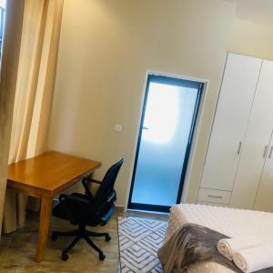 The Residence Hills BnB في هراري: غرفة نوم مع مكتب وكرسي بجوار سرير