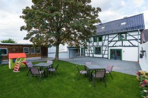 ein Hof mit Tischen und Stühlen vor einem Haus in der Unterkunft Ferienhaus Ahorn, wunderschöne, neue Wohnungen, ideal für Ausflüge ins Phantasialand, die Städte Köln, Brühl und Bonn oder die Eifel in Weilerswist