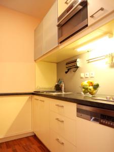 a kitchen with white cabinets and a bowl of fruit on the counter at Apartments City Centre in Bratislava