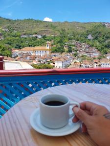 a person holding a cup of coffee on a table at Pousada Ouro Preto in Ouro Preto