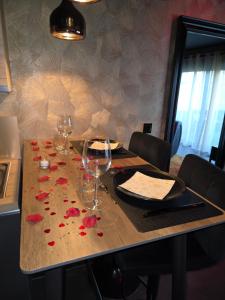 a wooden table with wine glasses and red flowers on it at Avec toi suite spa La Secrète in Barlin