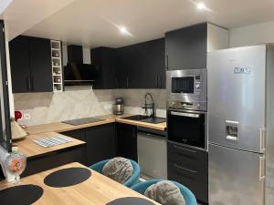 a kitchen with black cabinets and a stainless steel refrigerator at Maison moderne proche CDG in Aulnay-sous-Bois