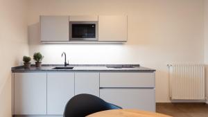 a white kitchen with a sink and a microwave at Apartments Hofgarten in Caldaro