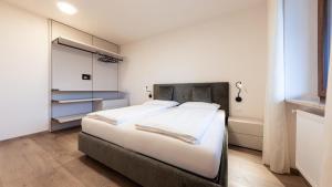 a bedroom with a large bed with white sheets at Apartments Hofgarten in Caldaro +38 photos