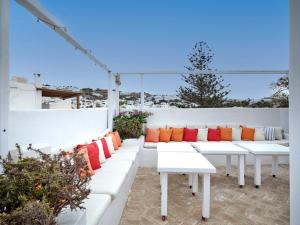 a row of white benches with colorful pillows at La Maison Kalogera in Mikonos