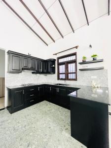 a kitchen with black cabinets and a black counter top at Fanisha Family Villa and Restaurant in Negombo