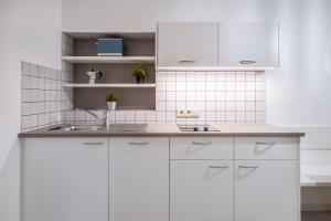 Una cocina blanca con gabinetes blancos y un fregadero. en Apartments Palma, en Cortaccia