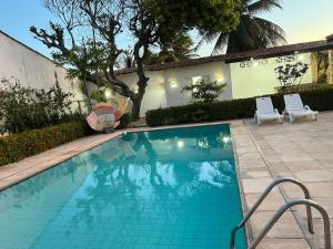 a swimming pool with two chairs and a house at Praia Marina Suite - Morro Branco in Beberibe +5 photos