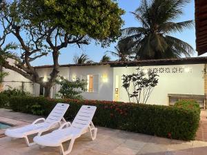 two white lawn chairs sitting in front of a house at Praia Marina Suite - Morro Branco in Beberibe
